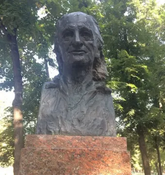 Bronze bust of Grigore Vieru on a granite pedestal in a tree-lined park.