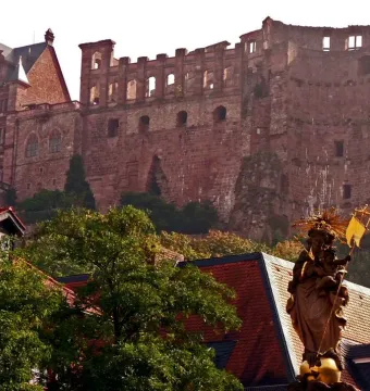 Kornmarkt Madonna standing above tiled rooftops with Heidelberg Castle in the background
