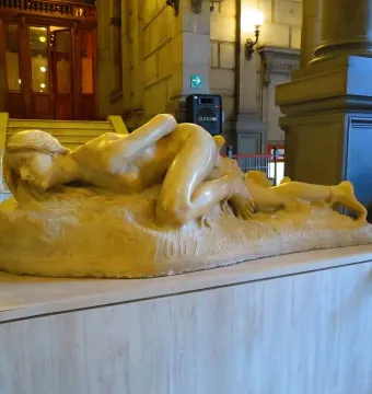 Malgré Tout sculpture of a reclining nude female figure in a grand museum interior
