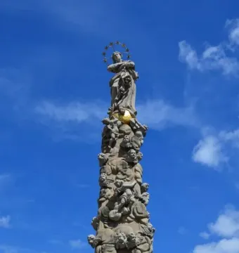Marian Column in Košice with a tall carved stone column topped by a female statue and halo of stars.