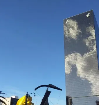 Puerta 1808 sculpture in a plaza with a reflective skyscraper and a yellow sculpture nearby