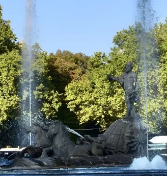 The Fountain of Neptune in Madrid with Neptune standing on a shell, flanked by two sea-horse figures and surrounded by jets of water.
