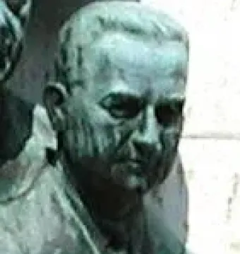 Bronze bust of Joseph L. Melnick with a green patina, shown in close-up against a pale wall.