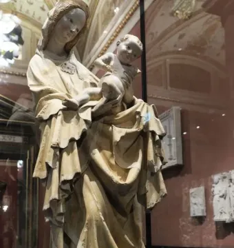 Krumlov Madonna sculpture of a robed woman holding a child in a museum case.