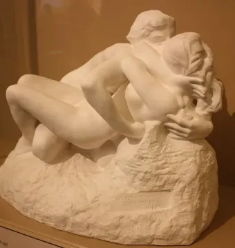 Metamorphoses sculpture of two intertwined nude figures embracing on a rough base