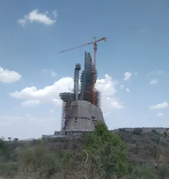 The Statue of Belief under construction, with scaffolding and a crane around its unfinished upper sections.