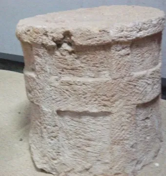 Roughly cylindrical stone section from the Giants of Mont\'e Prama with coarse tool marks and horizontal bands.