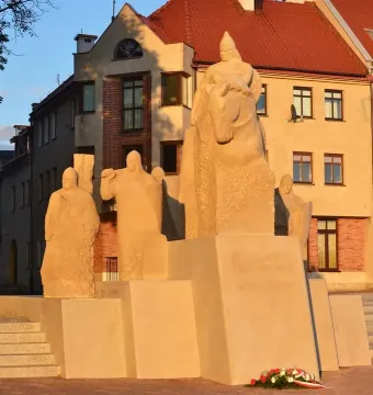 Bolesław III Wrymouth Monument with a mounted rider and figures on a stone pedestal, with a floral wreath at the base.