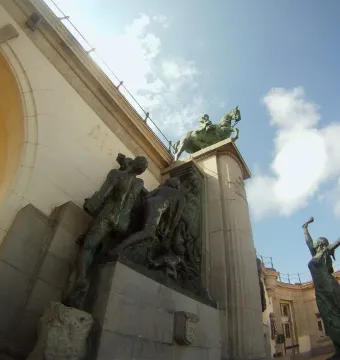 Monument of Leopold II bronze sculpture with a rider on horseback above standing figures against a stone structure and blue sky.