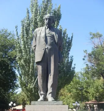 Bronze monument to Avetik Isahakyan on a stone pedestal in a park setting.