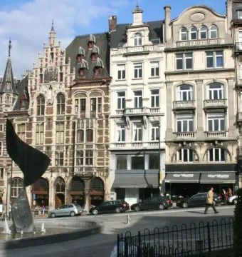 The Whirling Ear sculpture rises from a fountain, with historic buildings behind it on a city street.