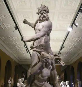 Neptune and Triton marble sculpture by Bernini shown in a museum hall, with a standing bearded figure over a kneeling figure covering his face.