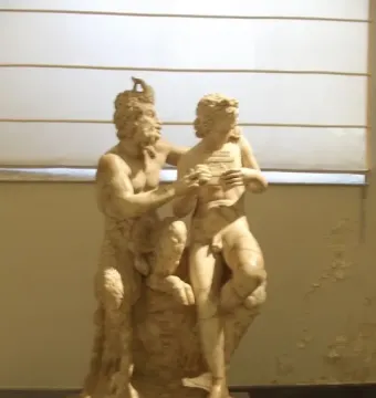 Pan and Daphne marble sculpture showing a bearded, horned figure embracing a nude figure holding an object to the chest.