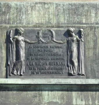 Weathered bronze plaque with two classically draped female figures holding a laurel wreath and an inscription beneath the dates 1822 and 1922.