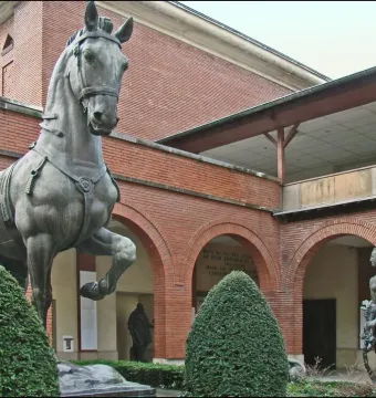 Bronze horse from the Monument to General Carlos M. de Alvear stands in a courtyard with brick arcades and smaller bronze figures.