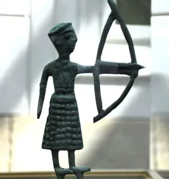 Nuragic bronze statuette of an archer holding a bow on a small base.