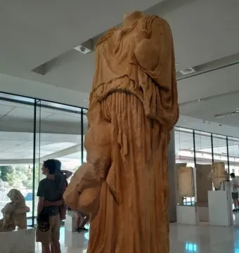 Procne and Itys sculpture displayed in a bright museum gallery with other antiquities in the background.