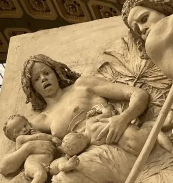Close-up of The Nubians sculpture showing a distressed woman holding two infants among foliage, with a long stick crossing the lower right.