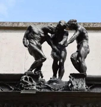 The Three Shades by Rodin, showing three dark bronze nude figures grouped together with bowed heads.