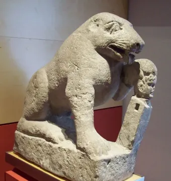 Bear of Porcuna stone sculpture showing a seated bear with one paw resting on a small herma topped by a human head.