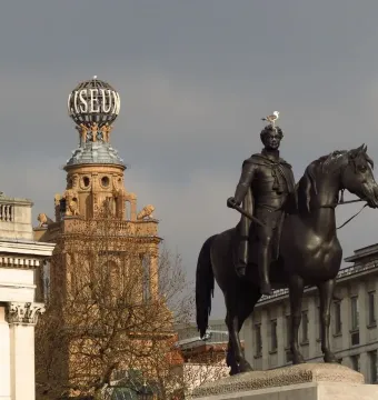 Equestrian statue of George IV on horseback atop a stone pedestal, with a seagull perched on his head.
