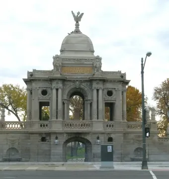 Hurlbut Memorial Gate with a stone arched entrance, cupola, and eagle statue on top.