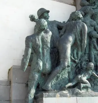 Close-up of the Monument of Leopold II showing a bronze relief group with men, women, and children around a central standing figure.