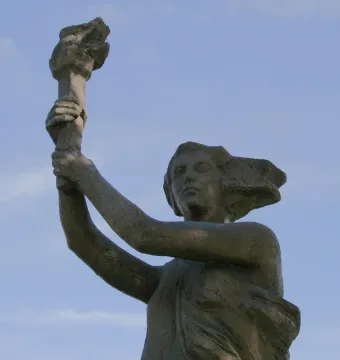 Victims of Communism Memorial statue of a female figure holding a torch aloft against a blue sky.