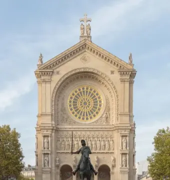 Joan of Arc equestrian statue on a stone pedestal in front of an ornate cathedral facade with a golden rose window.