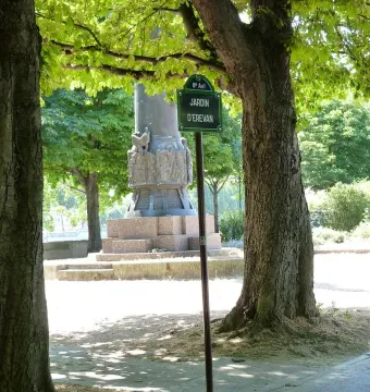 Lower section of the Monument to Mickiewicz, showing a sculpted stone base between trees near the Jardin d\'Erevan sign.