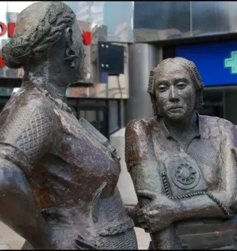 The Monument to the Unknown Woman Worker showing two bronze female figures, one seen from behind and the other facing forward with a rotary phone motif.