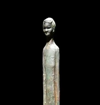 Ombra della sera bronze figure with an elongated body and a weathered greenish-brown patina against a dark background.