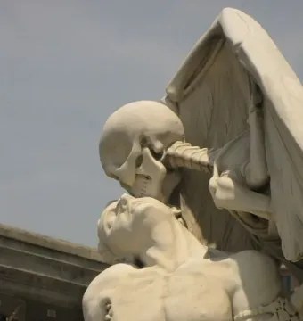 The Kiss of Death sculpture showing a skeletal figure leaning over a bare-chested man with its face pressed to his forehead.