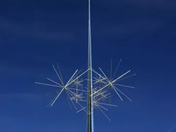 Ad Astra sculpture with a tall metallic pole and white starburst rods against a blue sky.