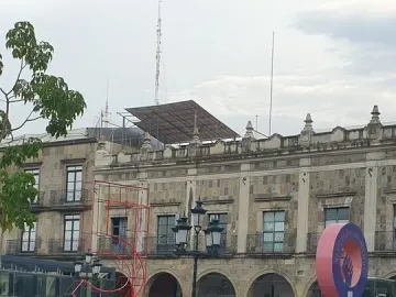 Crowd gathered in a plaza beside the Antimonumento 5J, with banners on the ground in front of an ornate stone building.