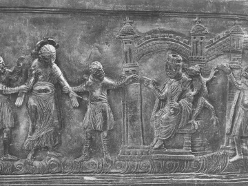 Bronze relief panel from the Bernward Doors showing several figures, a seated crowned ruler, stylized buildings, and a small dragon-like creature.