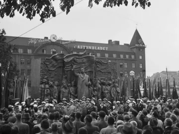 The Branting Monument shows a bronze figure addressing a crowd of workers with banners, with people gathered in front and the Aftonbladet building behind.