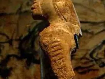 Lion-man figurine with a lion-like head facing left, shown against a dark blurred background.