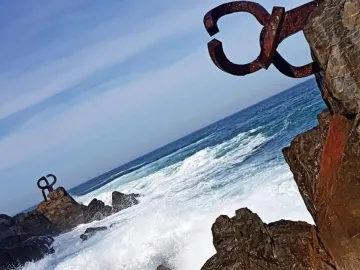 Peine del Viento rusted steel sculptures on coastal rocks with waves and the sea beyond