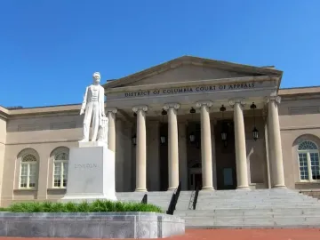 Abraham Lincoln marble statue on a stone pedestal in front of a classical courthouse building