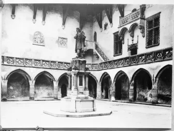 Copernicus Monument in a gothic courtyard, showing a robed statue holding a spherical instrument on a decorated pedestal.
