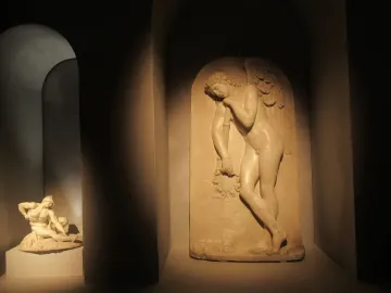 Marble bas-relief in the Monument to Elena Pavlovna, showing a winged male figure holding a garland and staff in an arched niche.