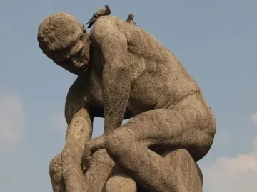 Tauzieher stone sculpture of a muscular man pulling a thick rope beside a stone bollard, with two pigeons on his back.