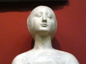 White marble bust of a princess with stylized features and pulled-back hair on a dark base.