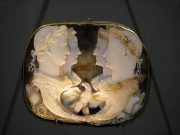 Gemma Claudia oval onyx cameo with four profile figures in relief and a gold border.