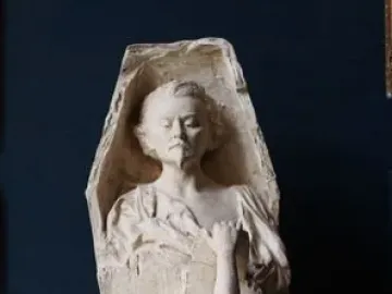 La Gloire sculpture showing a nude female figure reaching upward and pulling apart a tall structure with a man\'s bust at the top.