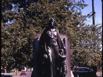 Pioneer Mother Memorial bronze statue of a woman on a stone base, flanked by smaller figures and surrounded by trees.