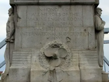 Titanic Engine Room Heroes Memorial stone inscription with carved figures, a ship\'s propeller, wreath, and anchor relief.