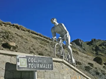 Géant du Tourmalet sculpture of a cyclist climbing against rugged mountain peaks.
