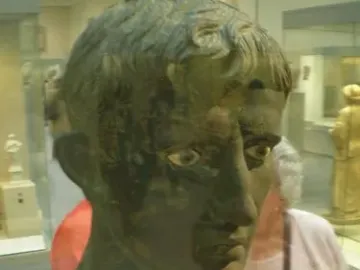Meroë Head bronze sculpture with short curly hair and prominent eyes on a pedestal